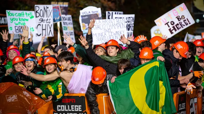 Oregon fans with signs at College GameDay, wearing orange hard hats and holding Oregon flag